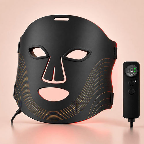 Red light facial mask therapy device with a black contoured mask and a separate handheld controller, shown on a soft peach background.